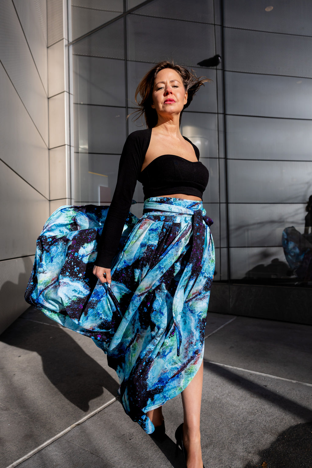 A woman wearing a black top and a Sarah Camille Art blue floral bamboo fiber skirt with pockets, standing in NYC 