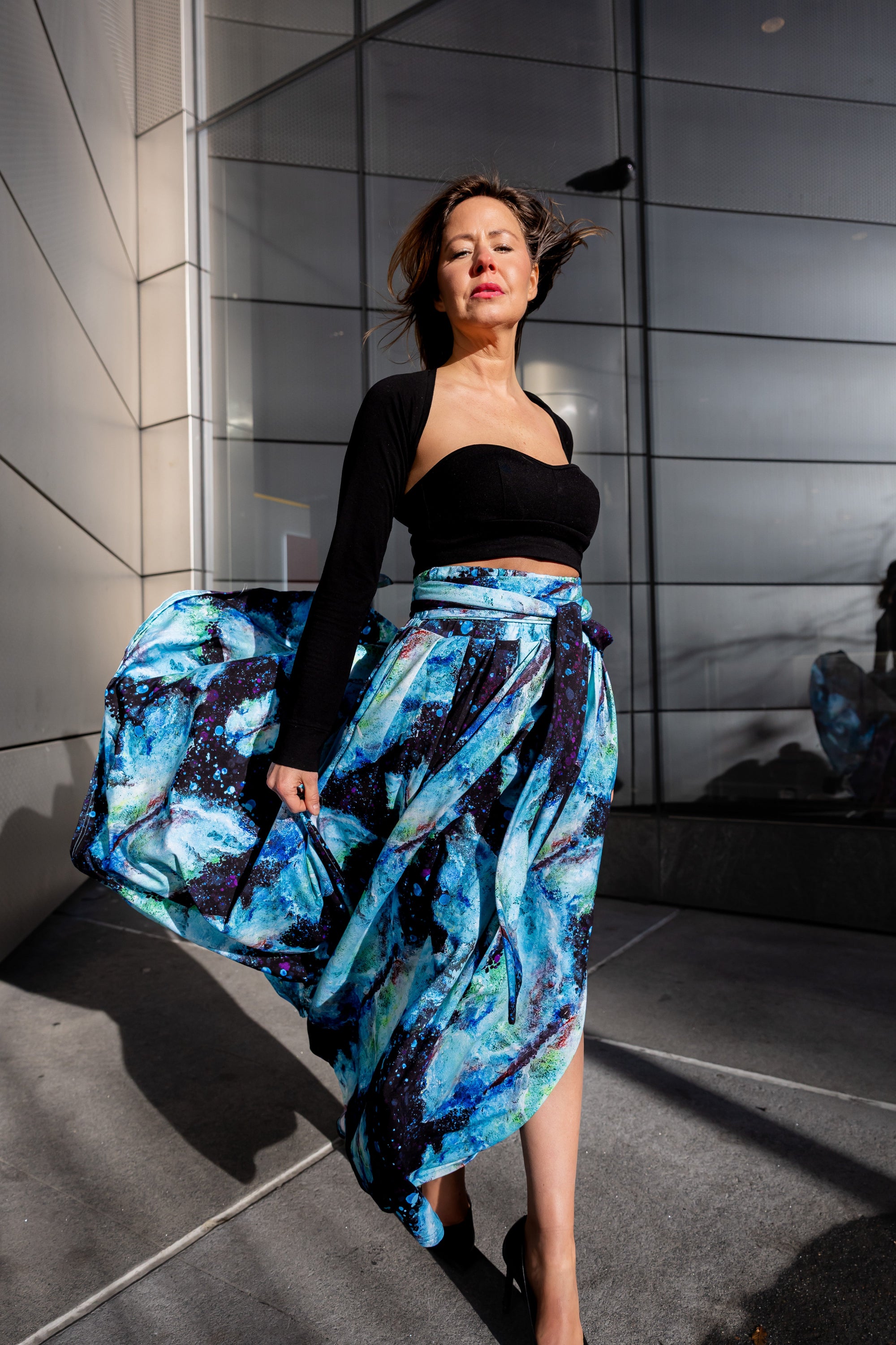 A woman wearing a black top and a Sarah Camille Art blue floral bamboo fiber skirt with pockets, standing in NYC 